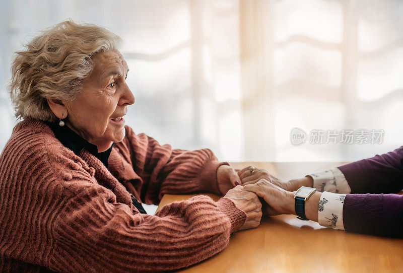 一个老妇人牵着另一个女人的手微笑的特写。只看到一个人。老年关怀和关怀的概念。养老院。