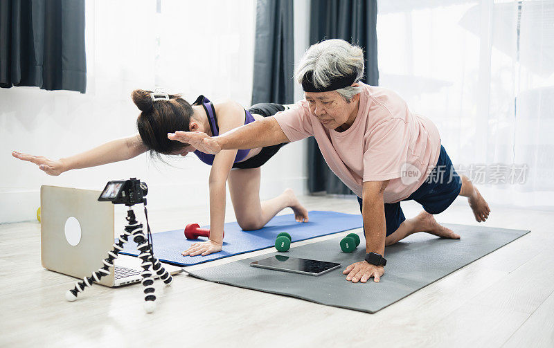 概念老年人在家里锻炼，亚洲老年妇女和亚洲青少年妇女在客厅锻炼的视频指南，从笔记本电脑和摄像机录制视频。