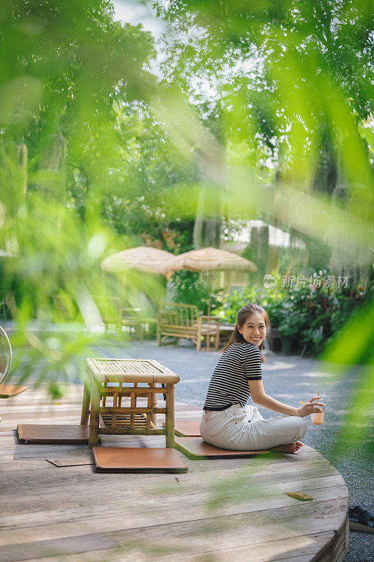 快乐迷人的年轻女子坐在享受自然氛围下的夏季树新鲜空气