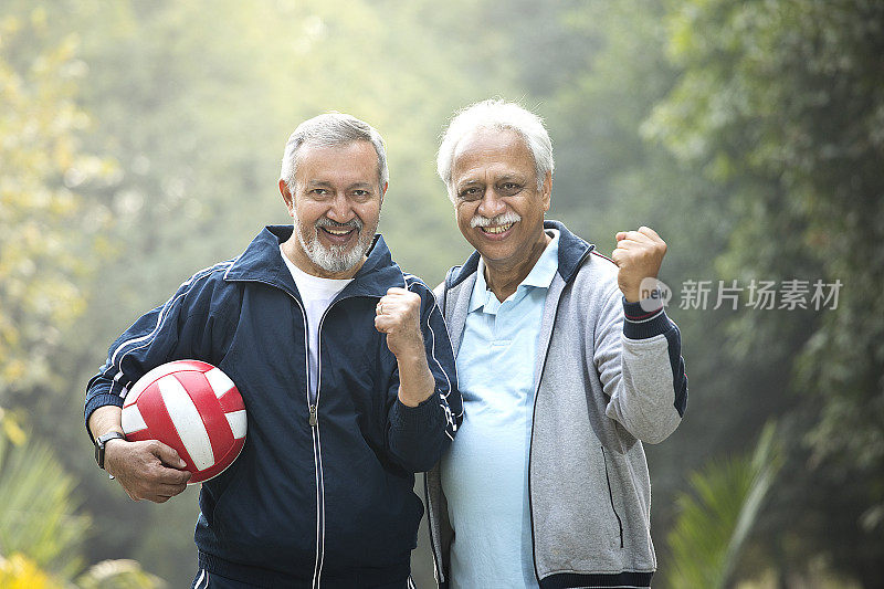 两个老人在公园里拿着运动球庆祝成功