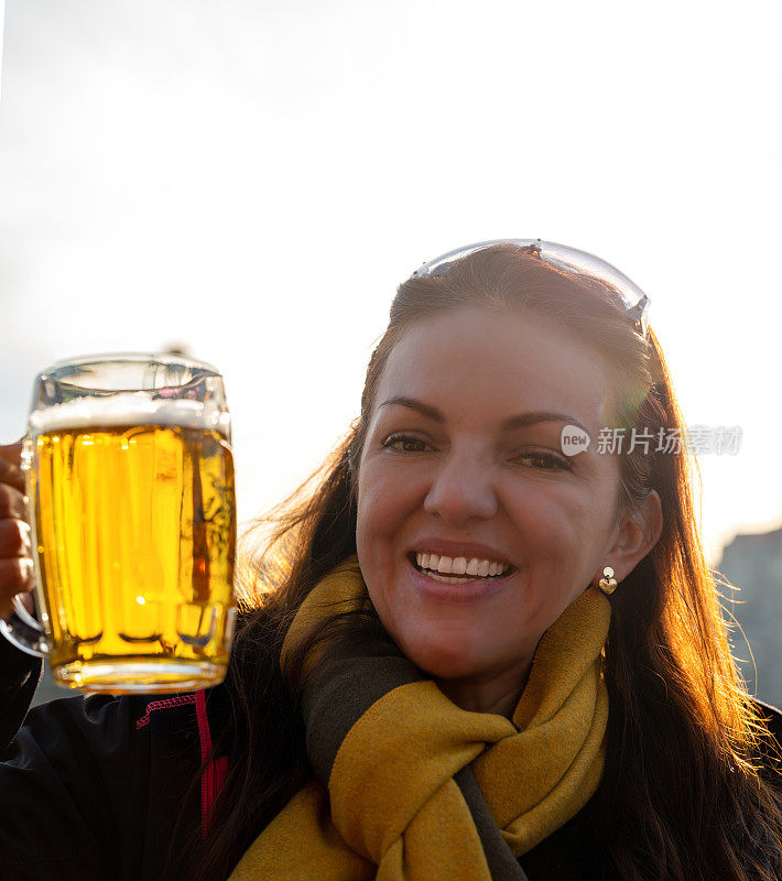 一个快乐的女士用大杯子喝啤酒的特写