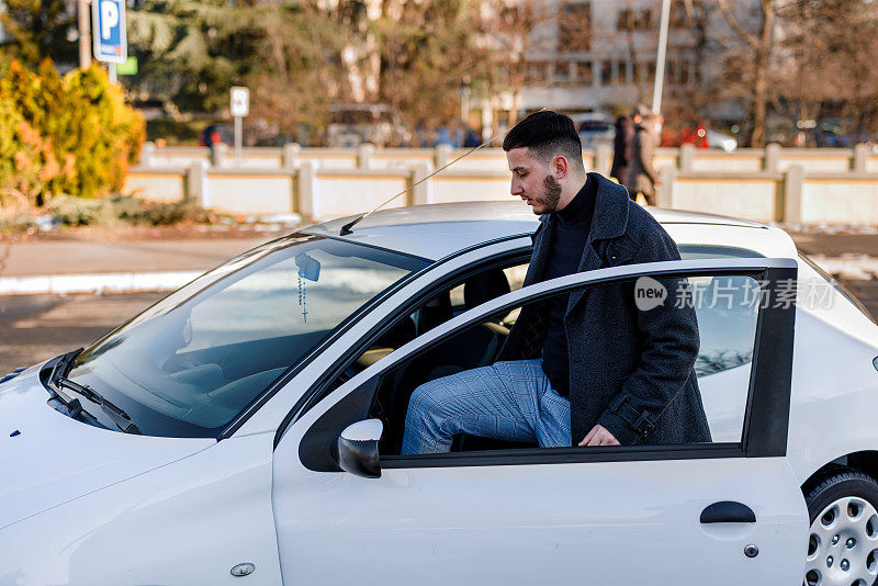 一个年轻时髦的男人正在街上走进一辆汽车。