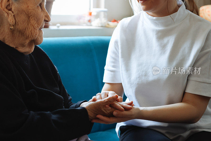 老女人的手牵着年轻女人的手，伸出援手，照顾老人的理念。