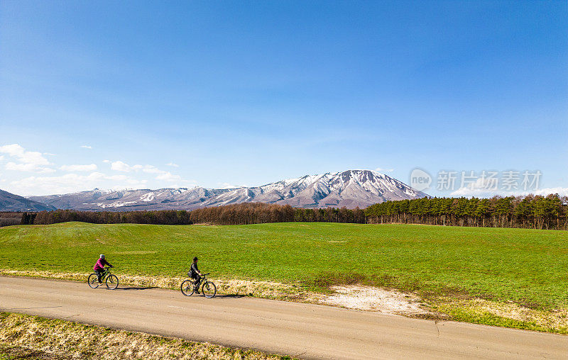 两个人骑着自行车沿着乡村公路欣赏山景