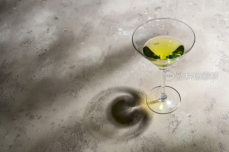 马提尼杯与鸡尾酒混凝土背景与阴影。