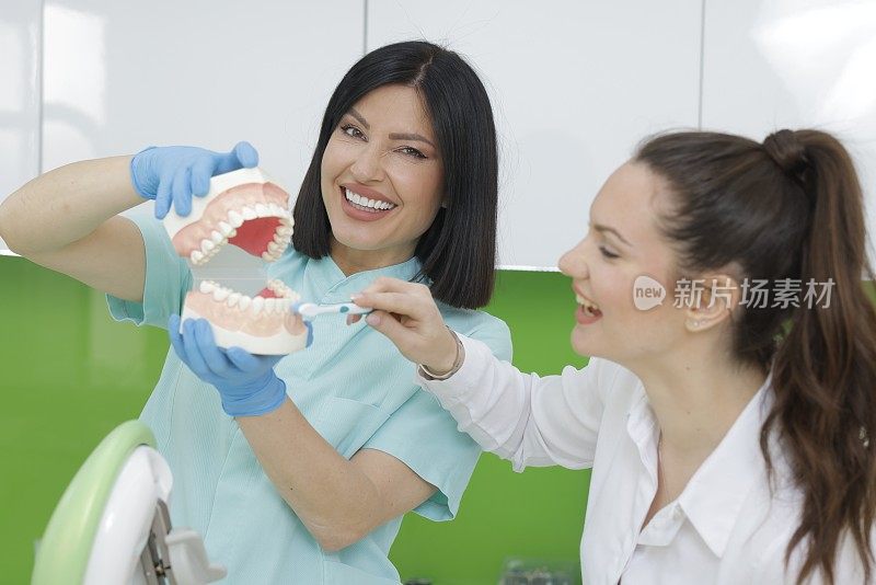 牙医。口腔卫生，教育。在牙齿模型上示范正确的刷牙方法。真人女牙医。