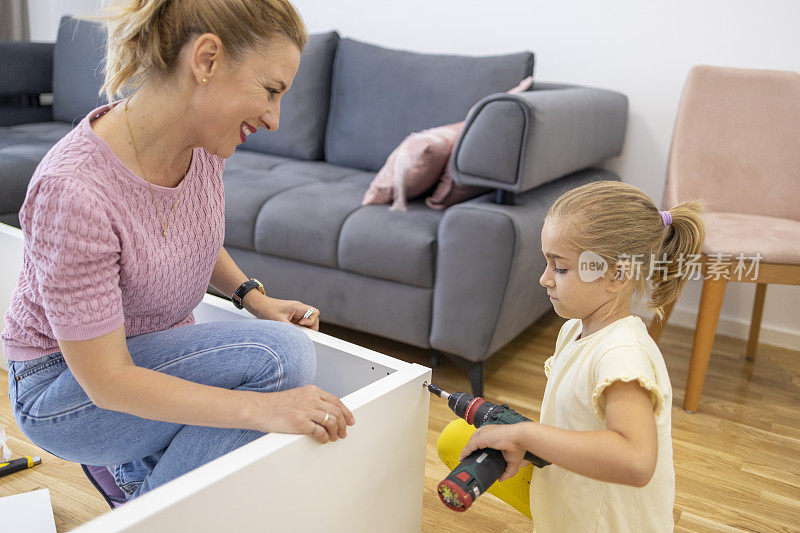 妇女用工具组装家具，和女儿玩得很开心