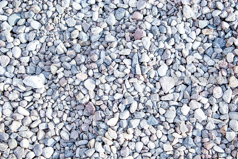 光滑的圆形鹅卵石纹理背景。卵石海沙滩特写，深色湿卵石和灰色干卵石