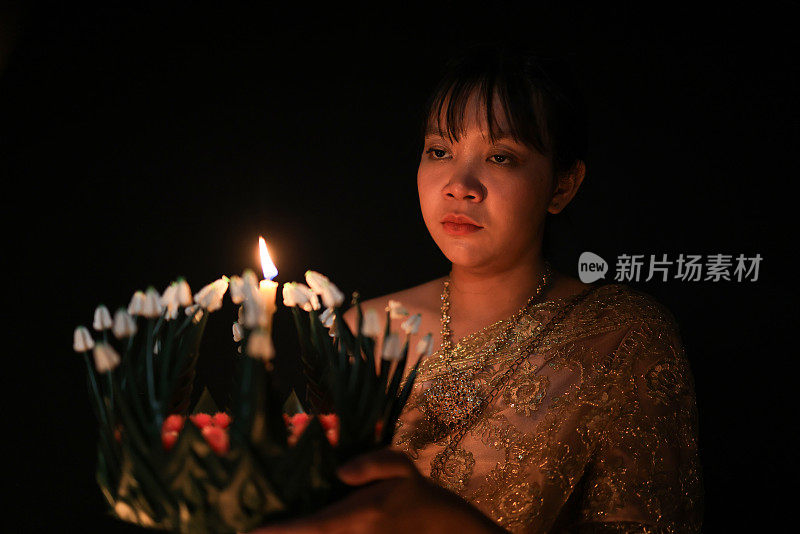 一位可爱的年轻女子穿着泰国传统服装，手拿“克拉通”向水神祈祷