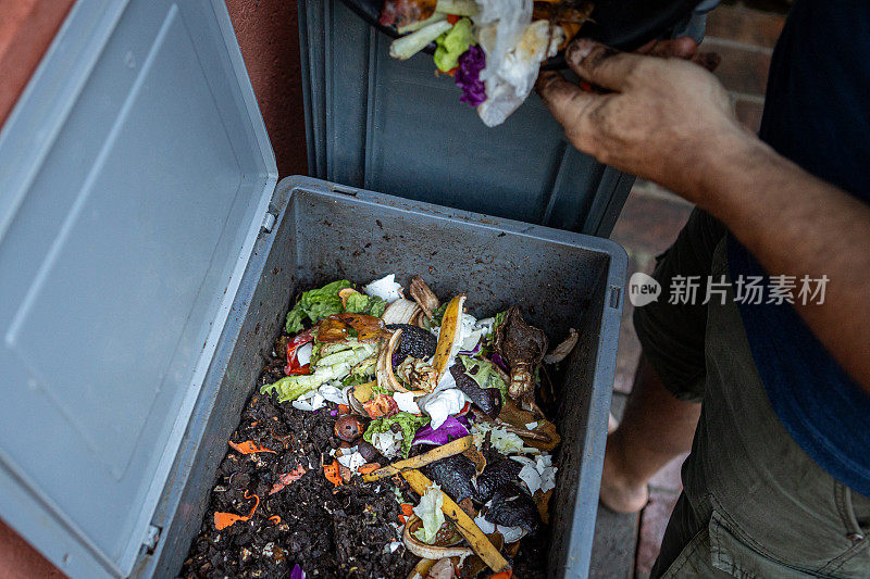 男子在家用堆肥机中堆肥有机残留物