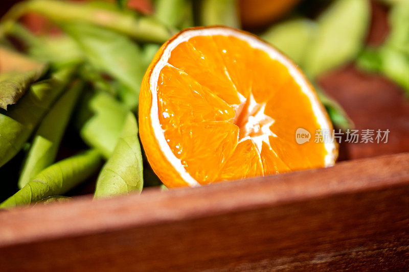 鲜艳的橙色水果片在阳光温暖的辉光下自然干燥，伴随着背景中绿叶的柔和散景，捕捉柑橘生产和有机生活。