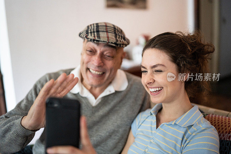 孙女和爷爷在家里用智能手机打视频电话
