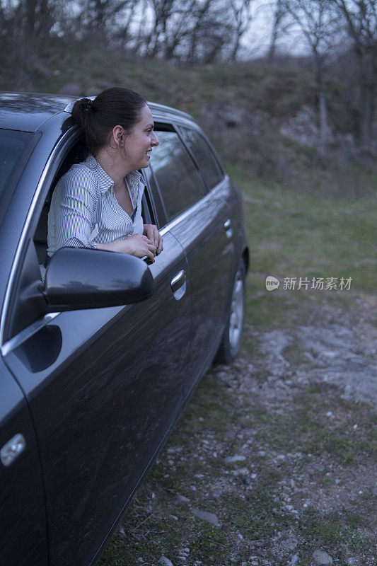 一个年轻女子站在车窗上，对着镜头摆姿势