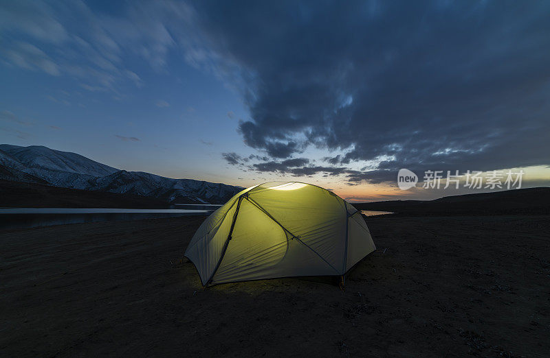 在沙滩上搭帐篷。日落后在湖边的山上露营。