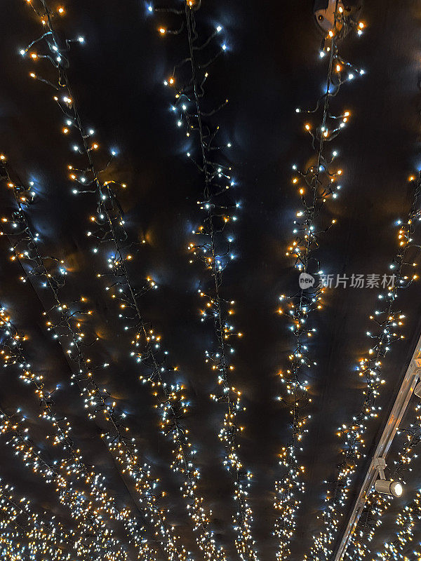彩色的圣诞彩灯装饰天花板的图像，从下面看LED彩灯，黑色背景