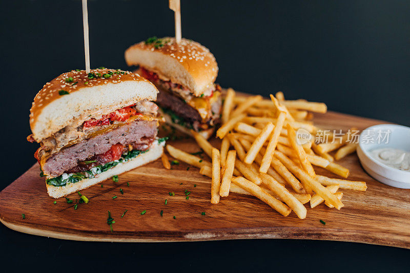 新鲜美味的汉堡，炸薯条和美味的酱汁在快餐店的木板上。