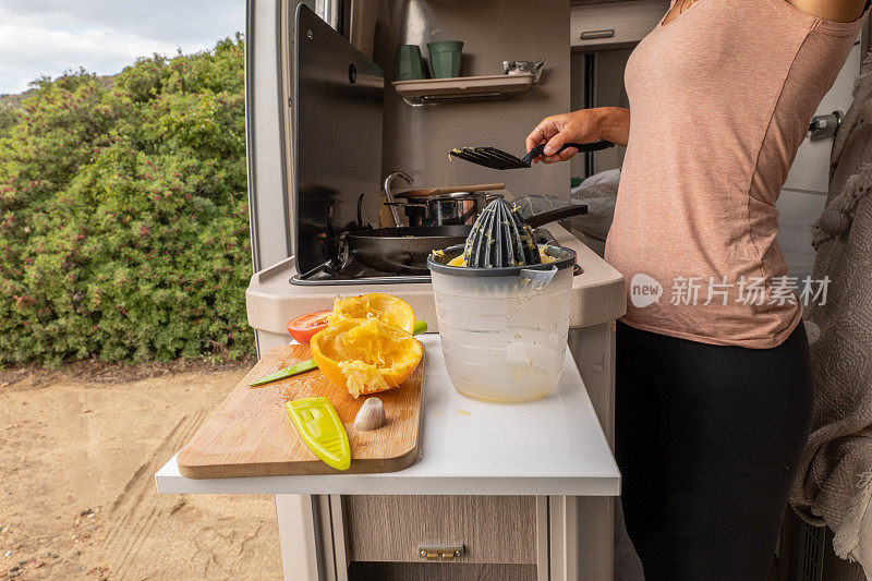 年轻女子在她的露营车里准备新鲜的早餐，面包车生活理念，她做了煎蛋卷