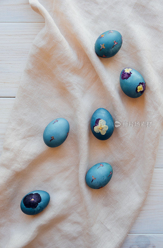 自然染色的青蓝压花复活节蛋在中性米色桌布背景。俯视图，平躺风格。手工工艺，天然装饰。