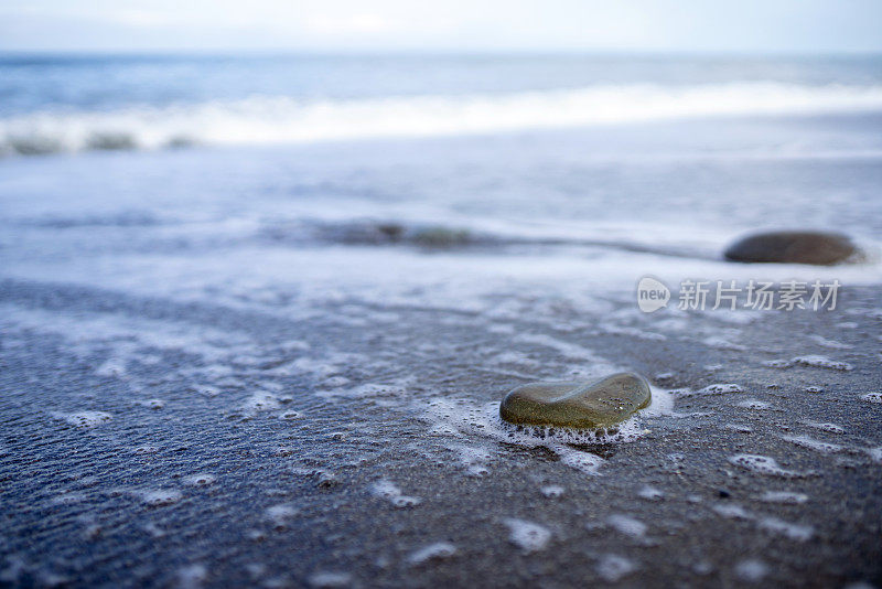 沙滩上湿卵石和海水泡沫的特写镜头