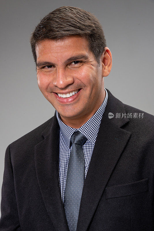 微笑成熟的拉美裔男子看着相机在灰色的背景