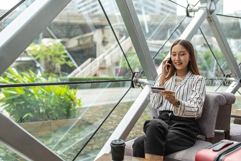 年轻聪明的亚洲女商人微笑快乐的电话，当信用卡呼叫中心批准她的临时信用额度增加