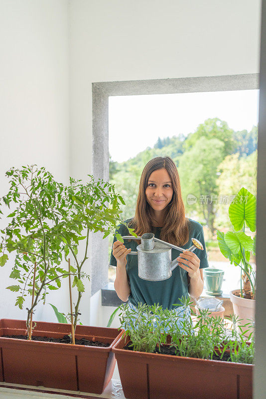 一名年轻女子在公寓露台上给植物浇水