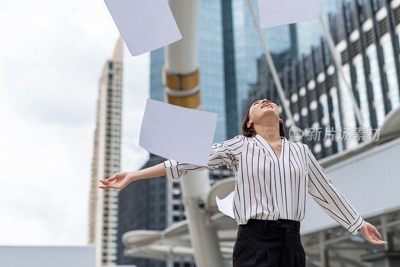 亚洲年轻漂亮的女商人在商业区把一堆文件纸扔向空中