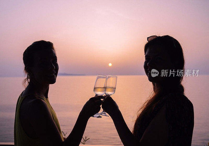 两名年轻女子在海滩边喝香槟敬酒。庆祝活动