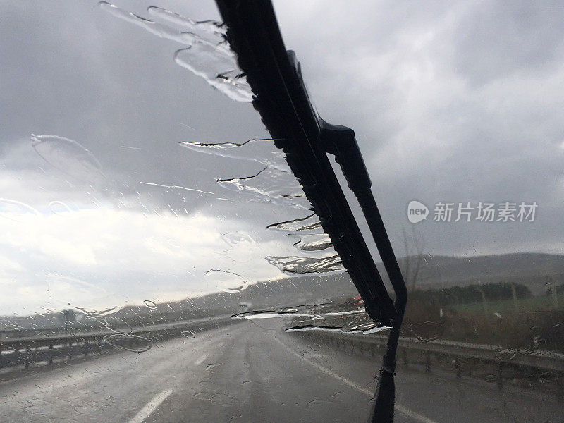 下雨天开车。雨刷带雨水和路面