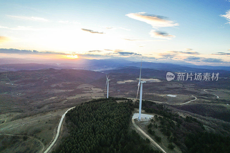 日落时的太阳能电池板和风力涡轮机。可再生能源