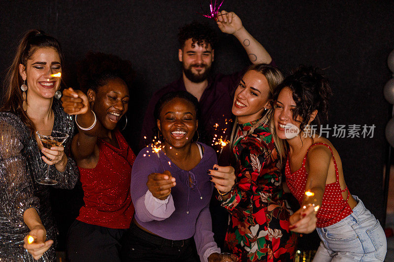 新年晚会上，一群快乐的朋友举着烟花，对着镜头开心地笑着