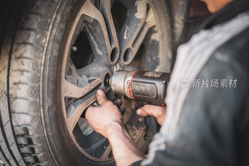 近距离观察在汽车修理厂更换车轮的技工