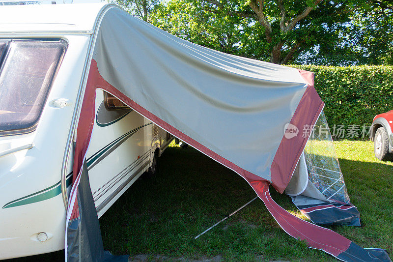 停在乡村准备度假的大篷车，但由于天气和风，遮阳篷已经倒塌，需要修理才能供家人使用。