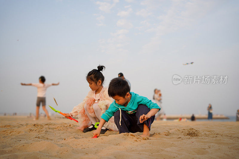 两个可爱的亚洲孩子在沙滩上堆沙堡