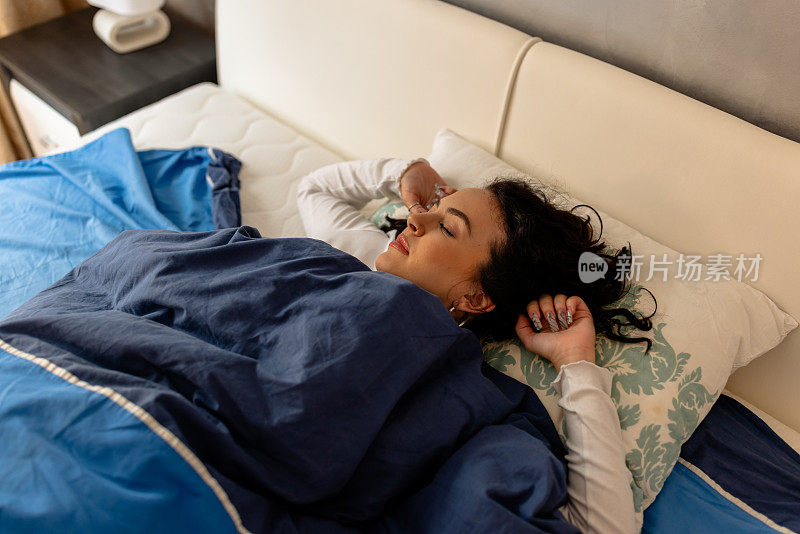 一个年轻漂亮的黑发女人正睡在一张舒适的床上。