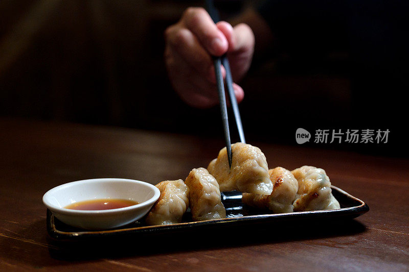 一名男子在餐厅用筷子夹饺子