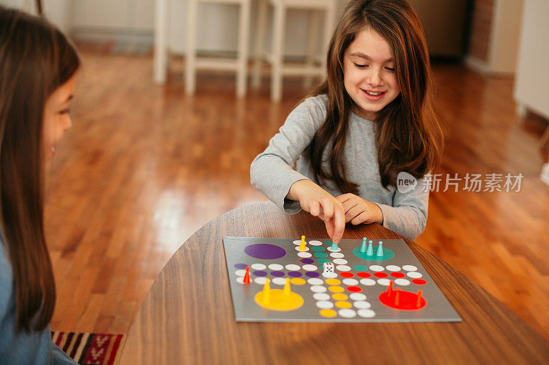 两个孩子在家里的桌子上玩棋盘游戏
