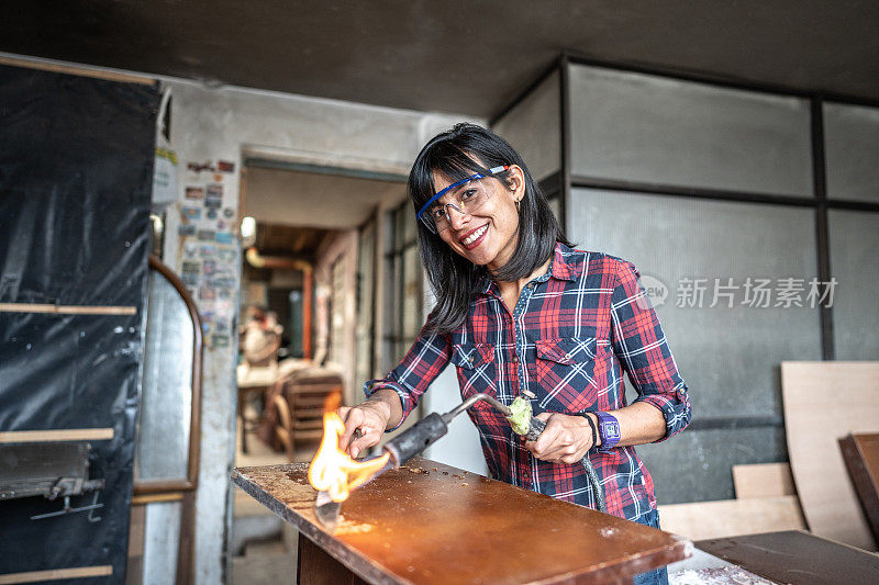 一个中年妇女的肖像，在木工工作中使用喷灯