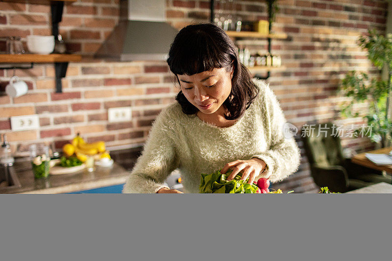 年轻的日本妇女在厨房里准备水果和蔬菜