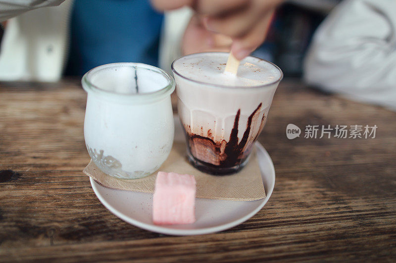 亚洲男孩正在用搅拌棒搅拌热巧克力牛奶