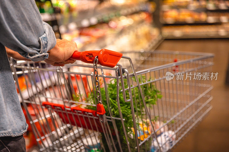 一名男子在超市里拿着一个购物篮，上面放着杂货