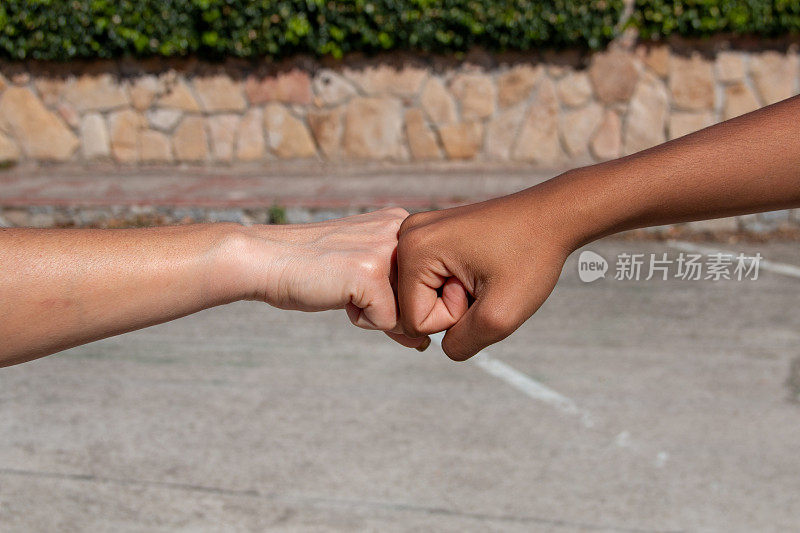 不同种族的手，非洲人和欧洲人，在友谊或同志情谊的概念中拳头碰在一起
