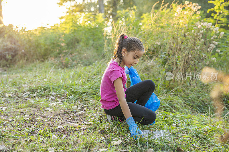 小女孩在河边捡塑料垃圾