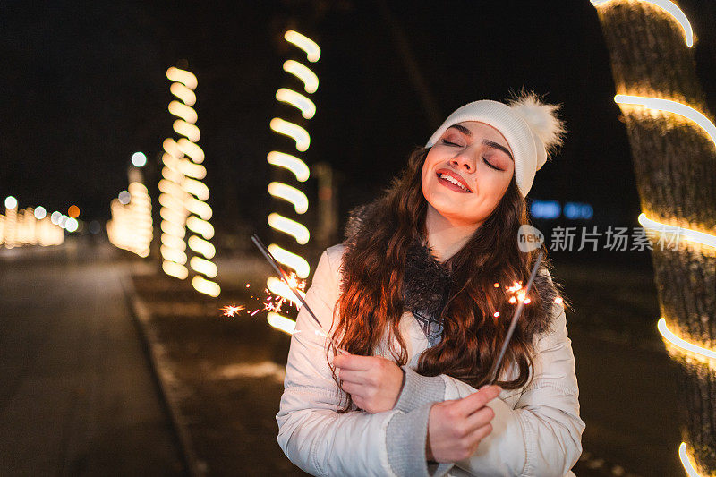 美丽的年轻女子手持烟花在户外庆祝除夕