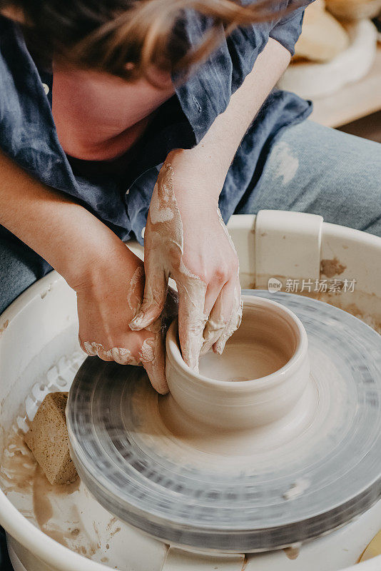 陶工的女性双手在车轮上塑造粘土制品