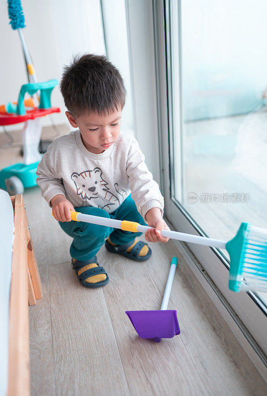 两岁半的小男孩一边愉快地打扫房子，一边玩家务活动