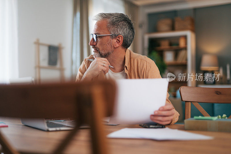 一个成熟的男人拿着一张纸，神情沉思。