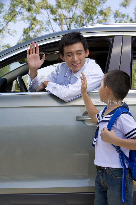 爸爸在车里向孩子招手送别