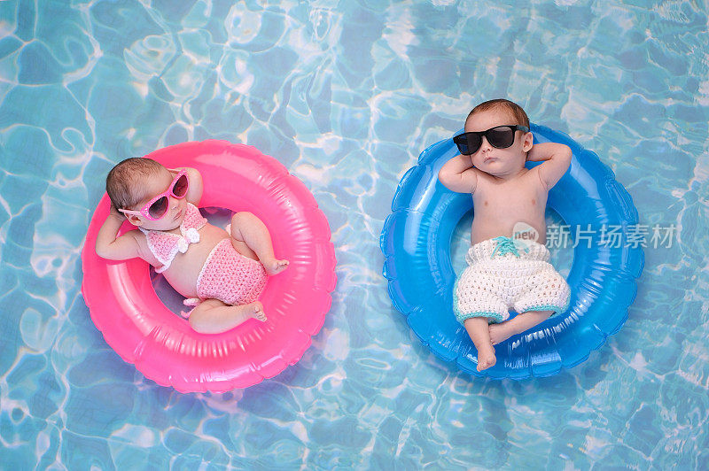 双胞胎男孩和女孩漂浮在游泳环上