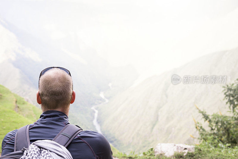 男性徒步旅行者坐着眺望高山和山谷